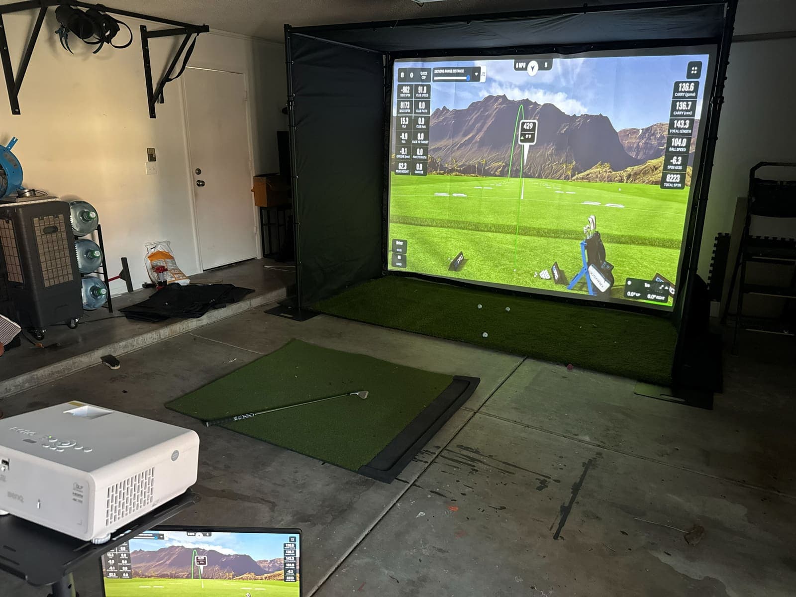 The whole garage with the factory sample deployed and a GSPro course on the screen, Oct 11, 2026. Phone photo.