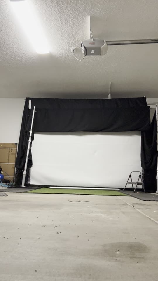 Photo of the same StowGolf prototype folded back against the garage wall, the floor in front of it clear